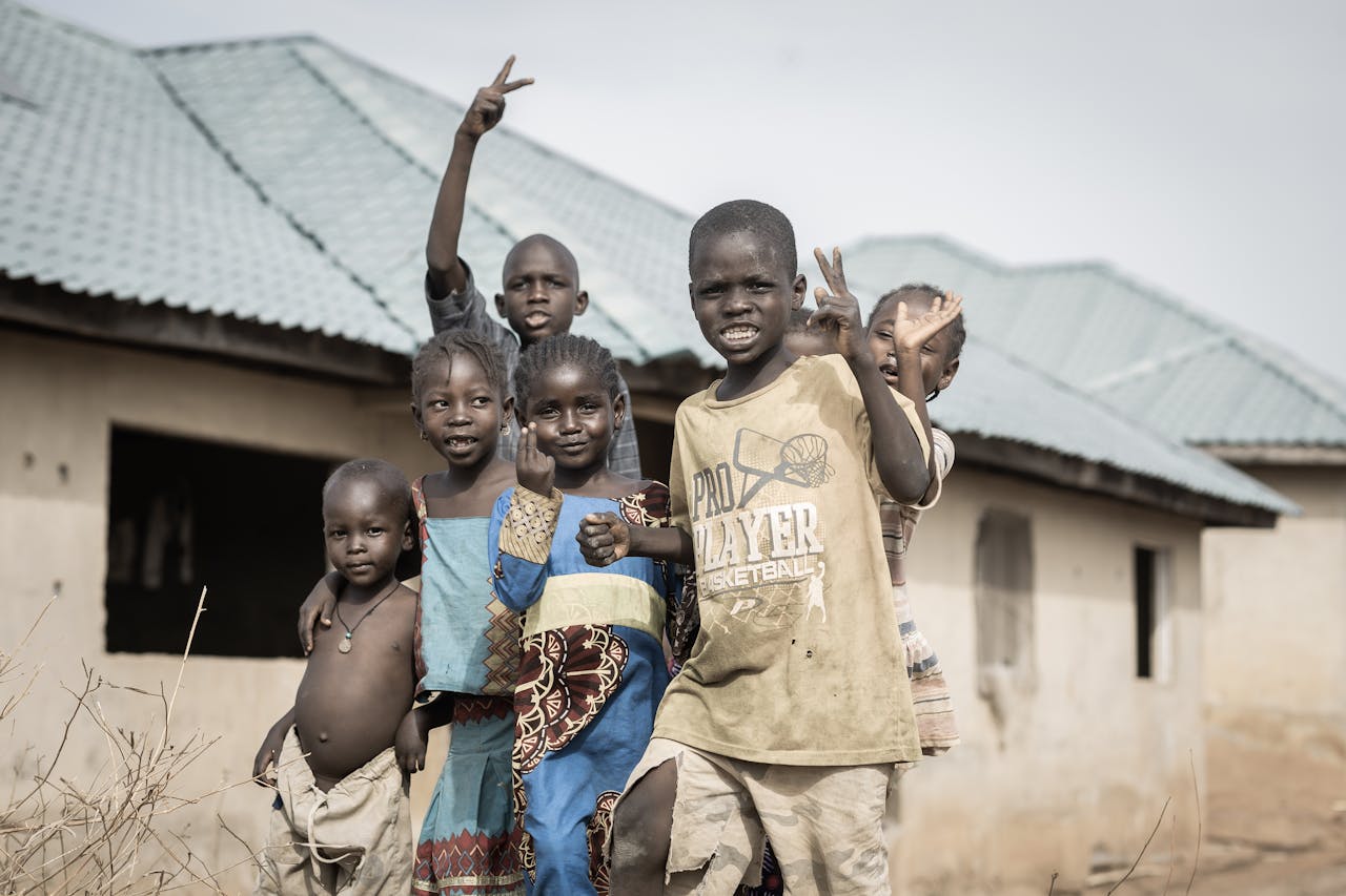 Group of children smiling and waving in a village in Nigeria, capturing friendship and joy.